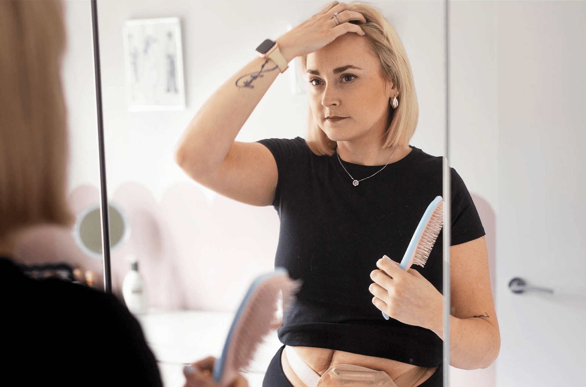 Woman with stoma looking in the mirror while brushing her hair