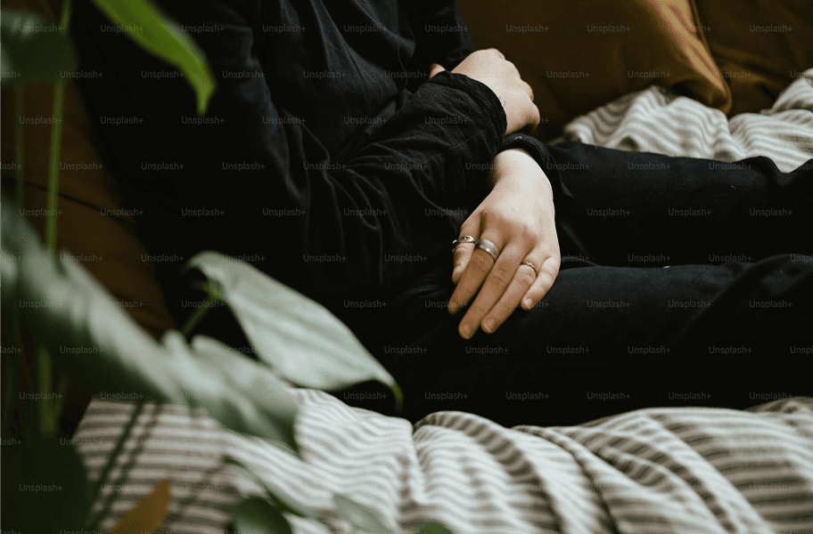 woman sitting on bed holding stomach